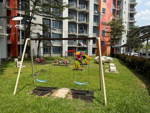 a park with a playground with swings in the grass at Bright Apartment in Klebang in Ipoh