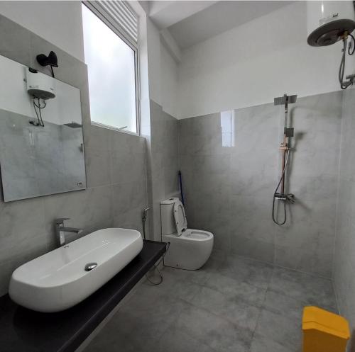 a white bathroom with a sink and a toilet at Mirissa Cocoon in Mirissa
