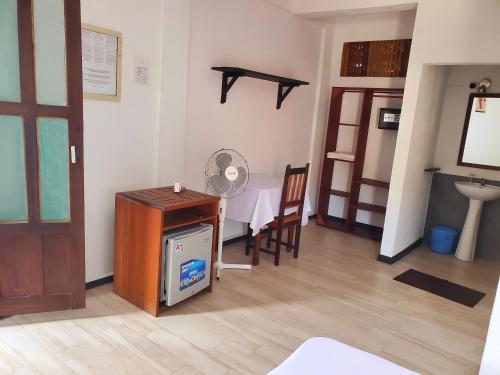 a room with a desk and a table and a fan at Hôtel chez Pat in Nosy Be