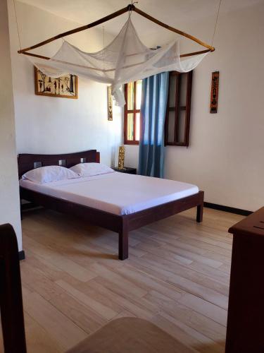a bed with a canopy in a room at Hôtel chez Pat in Nosy Be