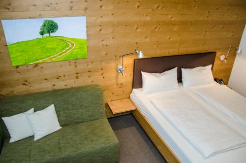 1 dormitorio con 1 cama y 1 sofá verde en Hofgut Farny en Kißlegg