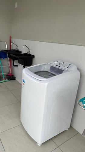 a white washing machine sitting on the floor in a room at House Box 02 in Itapema