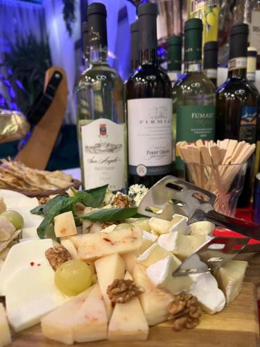 a table topped with cheese and bottles of wine at Hotel Les Jardins Carol in Bucharest