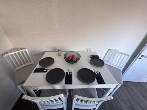a white table with three chairs and a bowl on it at Ovi Apartment in Vechta