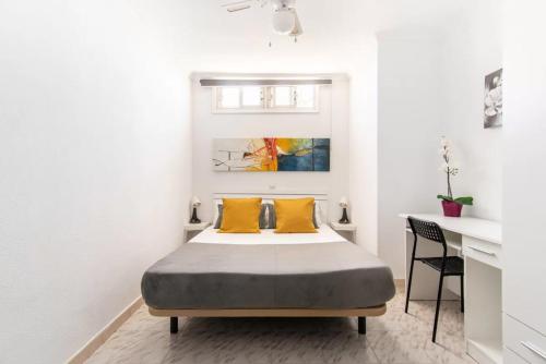 a bedroom with a bed with yellow pillows and a desk at Apartment 5 minutes from the sea in Playa del Ingles
