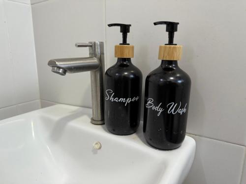 two black bottles sitting on top of a sink at Bright Apartment in Klebang in Ipoh