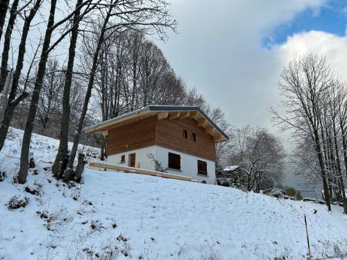 un petit bâtiment sur une colline enneigée dans l'établissement Le petit Ranch, à Le Reposoir
