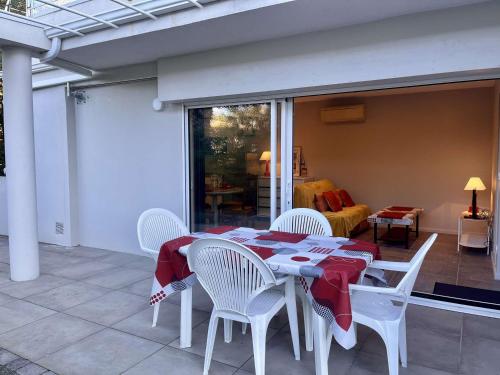 une table avec des chaises blanches et un tissu de table rouge dans l'établissement Calme Appartement T2 avec Terrasse à Cavalaire - FR-1-226B-2, à Cavalaire-sur-Mer