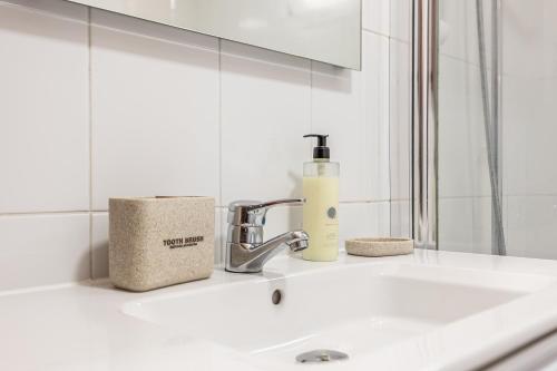 ein Waschbecken im Badezimmer mit einer Flasche Seife darauf in der Unterkunft Cozy Seaside Cottage Ocean Views and Near Beach in Caniço