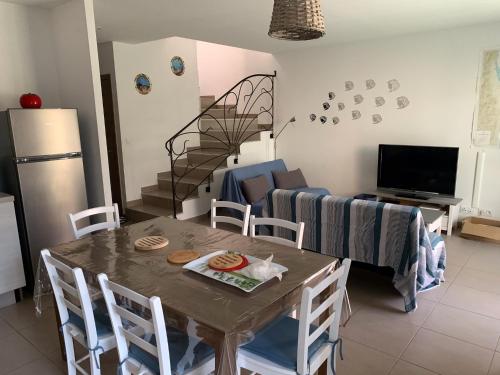 un salon avec une table avec des chaises et un canapé dans l'établissement Villa 1 Minute Du Bord De Mer Jardin Clim Wifi, à Santa-Lucia-di-Moriani