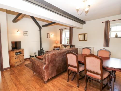 a living room with a leather couch and a table at Pencroft Cottage in Leyburn
