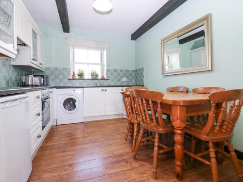 a kitchen with a table and chairs and a sink at Pencroft Cottage in Leyburn