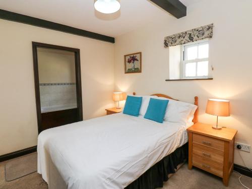 une chambre avec un grand lit blanc et une fenêtre dans l'établissement Pencroft Cottage, à Leyburn