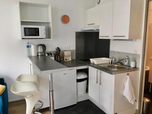 une petite cuisine avec des armoires blanches et un évier dans l'établissement Chaleureux Studio - Centre Ville Poitiers, à Poitiers