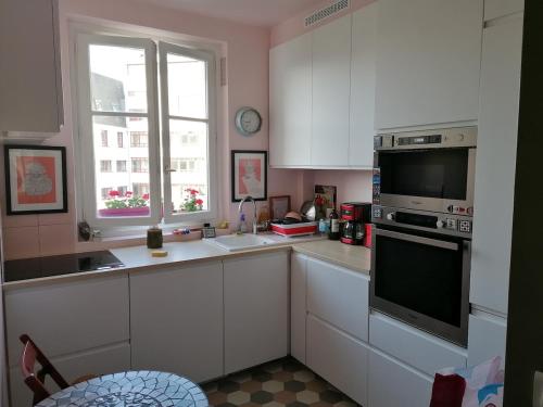une cuisine avec des armoires blanches et une fenêtre dans l'établissement Bel appartement Hausmannien au centre de Paris, à Paris