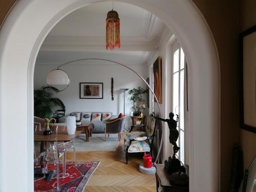 une arche menant à un salon avec un canapé dans l'établissement Bel appartement Hausmannien au centre de Paris, à Paris