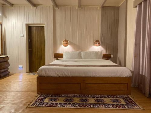 a bedroom with a bed with two lamps on the wall at MayaTels - Maya Eco Huts, Pelling in Pelling