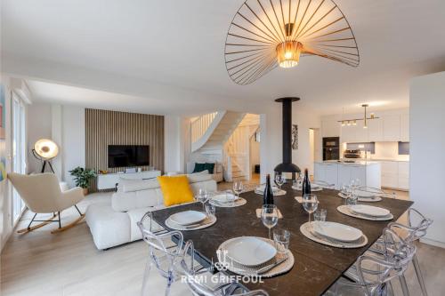 ein Esszimmer und ein Wohnzimmer mit Tisch und Stühlen in der Unterkunft Villa Canet - Jacuzzi - Fireplace - Sauna EV 10P in Gonneville-sur-Honfleur