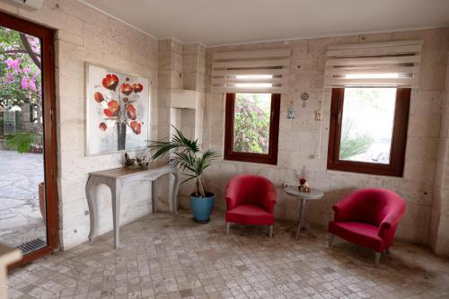 a living room with two red chairs and a table at Mare Garden Hotel in Akyarlar