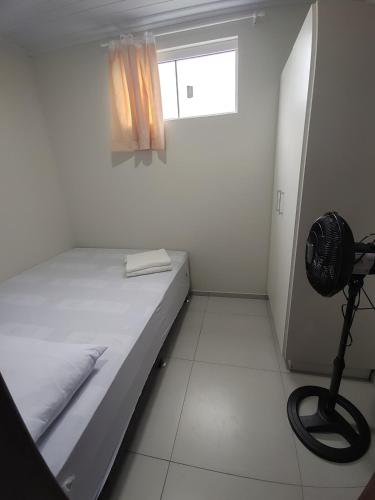 a small white room with a bed and a fan at Pousada Forquilhinha Vista-Mar in Arroio do Silva