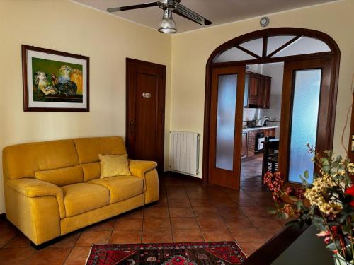 a living room with a yellow couch and a kitchen at B&B Conte Umberto Salemi in Salemi