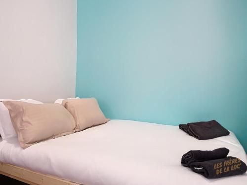 un lit avec des draps blancs et des oreillers dans une chambre dans l'établissement Appartement Lumineux - Cours Julien - Les Frères de la Loc', à Marseille