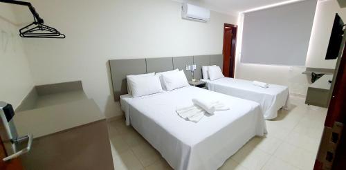 a hotel room with two beds with white sheets at Nordeste Palace Hotel - Glória-SE in Nossa Senhora da Glória
