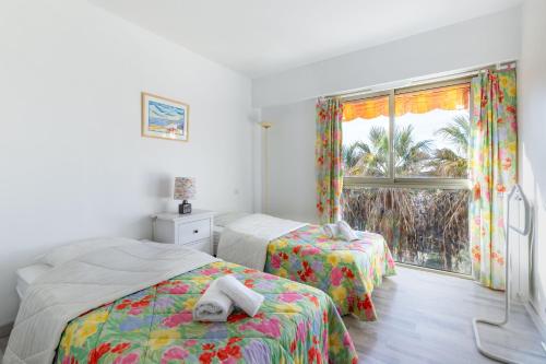 une chambre avec deux lits et une fenêtre dans l'établissement Happyfew appartement les palmiers, à Nice