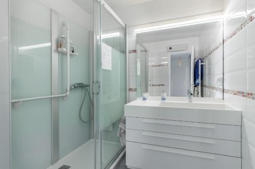 une salle de bain blanche avec une douche et un lavabo dans l'établissement Happyfew appartement les palmiers, à Nice
