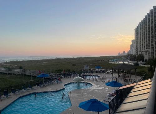 a large swimming pool with blue umbrellas and the ocean at Phoenix VIII-8206 by Vacation Homes Collection in Orange Beach