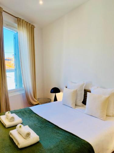 une chambre avec un grand lit blanc avec des serviettes dessus dans l'établissement 'Lazare' T3 Climatisé, Centre-ville, Wifi, à Sète