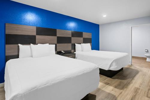 una camera da letto con due letti e una parete blu di Americas Best Value Inn-Gonzales a Gonzales