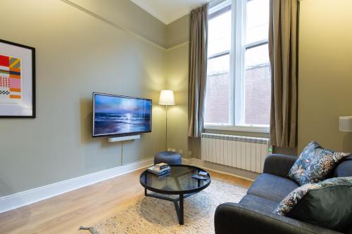 a living room with a couch and a table and a tv at Quiet City Centre, King & Sofa Bed in Glasgow