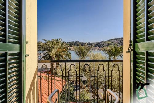 a balcony with a view of the water and palm trees at HOTIDAY Room Collection - Le Grazie in Portovenere