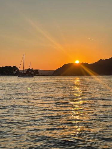 a sunset over a body of water with a boat at Guest House Plima 2 in Budva