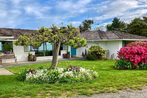 a house with a tree and flowers in the yard at Windrift House in Sequim
