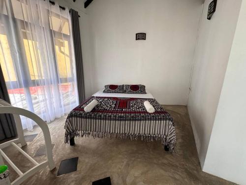 a bedroom with a bed in a room with a window at Mahaon surf hotel in Weligama