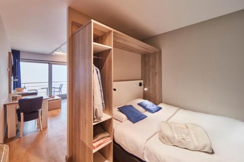a bedroom with a bed and a desk with a chair at Holiday Suites Blankenberge in Blankenberge