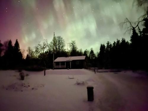 a cabin in the snow with the aurora in the sky at Stuga Näsberget in Malung