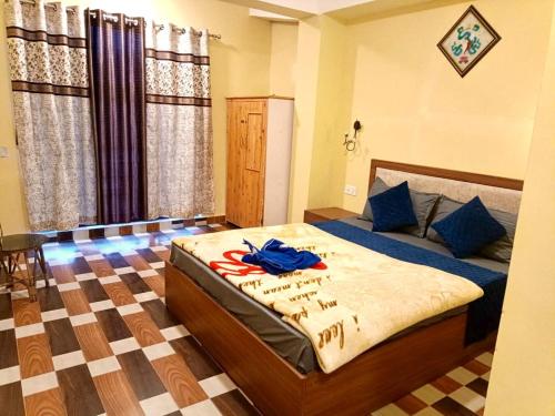 a bedroom with a bed with a blue shirt on it at Hotel Manjushree in Lava