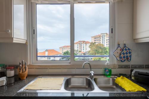 a kitchen counter with a sink and two windows at Madeira Sunny Penthouse in Funchal