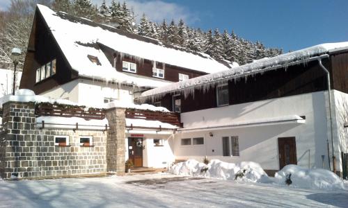 a building covered in snow with snow covered driveway at Penzion Bobešova bouda in Železná Ruda
