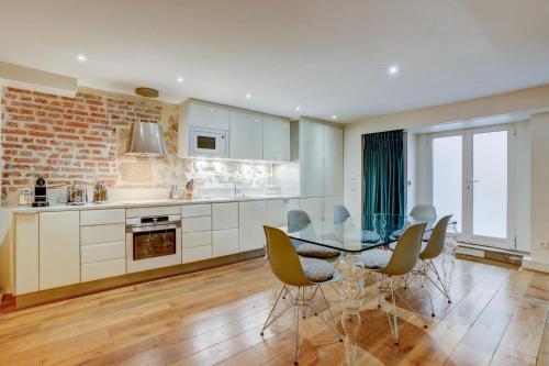 une cuisine avec une table et des chaises en verre dans l'établissement Jardin Prive - Gorgeous 3 Bed House in Le Marais, à Paris