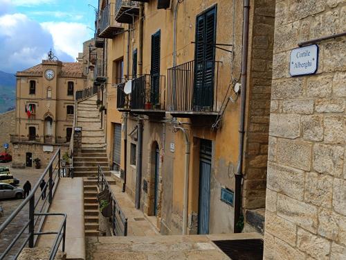 an alley with stairs and a clock on a building at Casa Vacanze Cortile Alberghi in Gangi