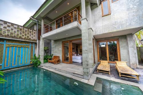 a house with a swimming pool and two chairs at Ubud Diary Villa in Ubud