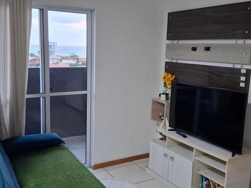 ein Wohnzimmer mit Flachbildfernseher und Fenster in der Unterkunft Apartamento linda vista para o mar Penha Parque Beto Carrero in Penha