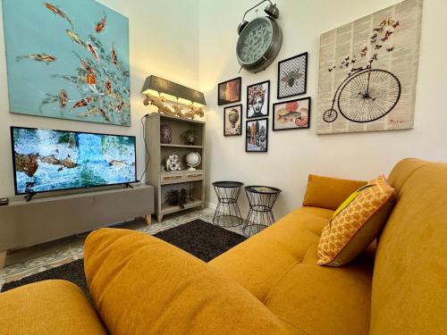 a living room with a yellow couch and a tv at Stylish Boutique Duplex Apartment Home - Orange - 2 Double Bedrooms in Hamrun