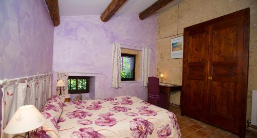 ボレーヌにあるMaison d'Hôtes Lou Genesteの紫の壁のベッドルーム1室(ベッド1台付)