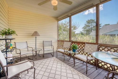 a screened porch with chairs and tables and windows at Sea La Vie - Duplex, Shared pool! in Chincoteague