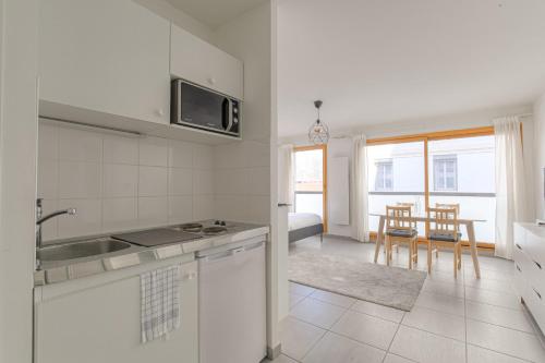une cuisine blanche avec un évier et une table dans l'établissement Cosy avec parking proche Brotteaux, à Lyon